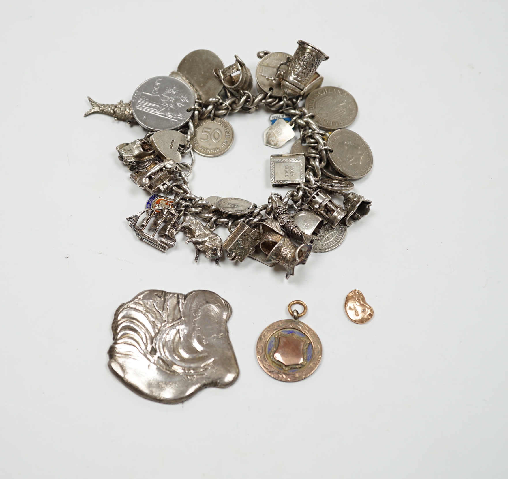 A silver charm bracelet, hung with assorted mainly white metal charms including tankard and Knight's helmet, two 'melted' ingots and a silver medallion.